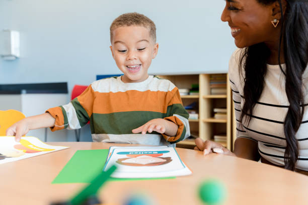 istock Cute preschool boy copies expression on picture card 1356661369