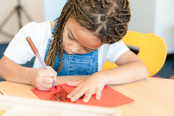 istock Kindergarten age girl concentrates on drawing 1356661374