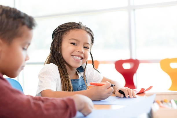istock Cute girl smiles for camera while coloring 1356661385