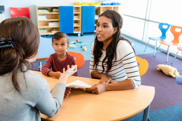 Mother listens to son's teacher during parent-teacher conference An attentive mother listens as her son's teacher discusses his progress during a parent teacher conference. primary school assembly stock pictures, royalty-free photos & images