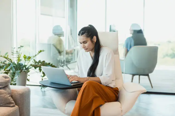 Photo of Businesswoman uses laptop in open concept office