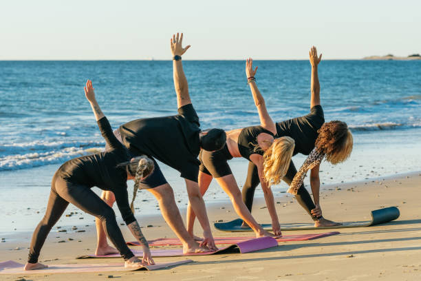 istock People of a yoga class stretching the back while doing yoga on the beach 1356665639