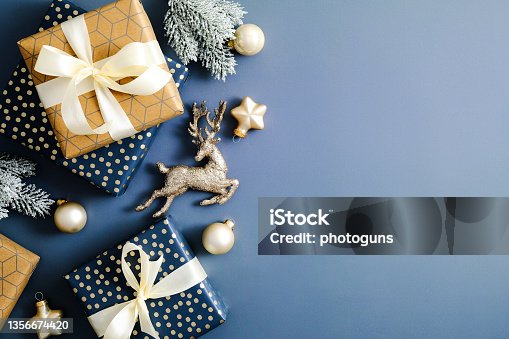 istock Elegant Christmas card mockup. Flat lay Christmas gifts, fir branches, decorations on blue table. Top view. 1356674420