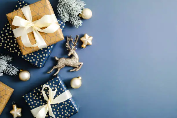 Elegant Christmas card mockup. Flat lay Christmas gifts, fir branches, decorations on blue table. Top view.