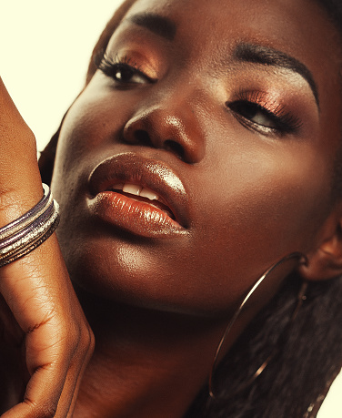 Beauty concept: Portrait of a sensual young African woman with colored make up, close up