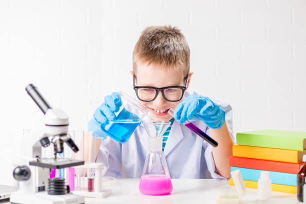 istock A schoolboy with a microscope and book examines chemicals in test tubes, conducts experiments - a portrait on a white background. Concept for the study of coronavirus in the laboratory 1356677022