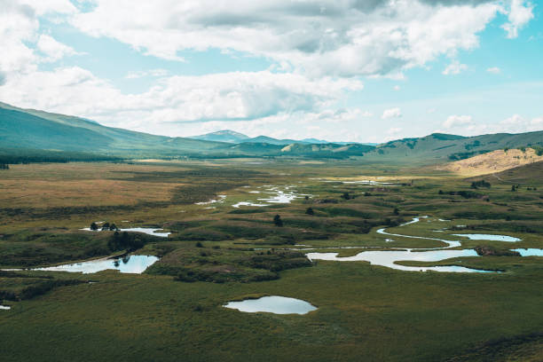 istock Surreal mountain scenery with lake system on tableland among forest hills. Scenic landscape with lakes group on plateau. Lakes system and channels in wide valley. System of lakes in surrealist colors. 1356677368
