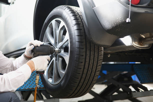 istock Automechanic with electric screwdriver changing tire in garage 1356677539