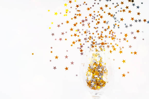 istock Christmas background.Simple minimalistic Christmas home decor.Flat lay,top view.Festive composition of a glass of champagne and glitter on a light background.Copy space. 1356677663