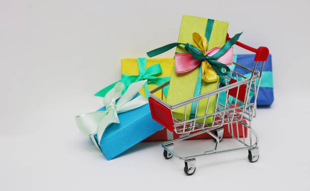 istock Shopping cart and four multi-colored gift boxes on a white background. 1356677700