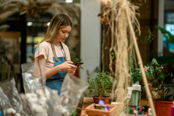 istock Florist using smartphone in a flower shop 1356678369