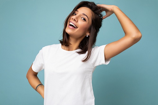 Photo of positive happy smiling young fascinating beautiful attractive nice brunette woman with sincere emotions wearing casual white t-shirt for mockup isolated over blue background with copy space for text.