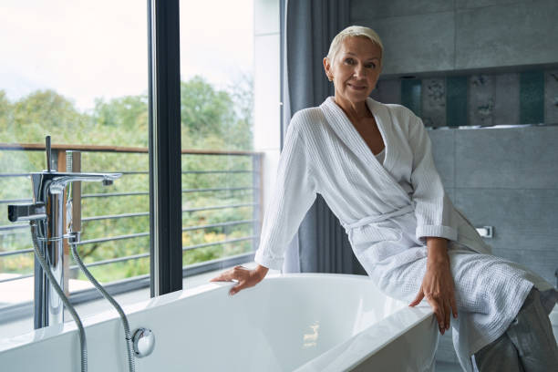 istock Pleased mature woman sitting on ceramic bath 1356679660