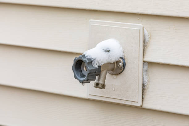 Outdoor water spigot covered in snow during winter. Home repair, maintenance and weatherproofing concept. stock photo