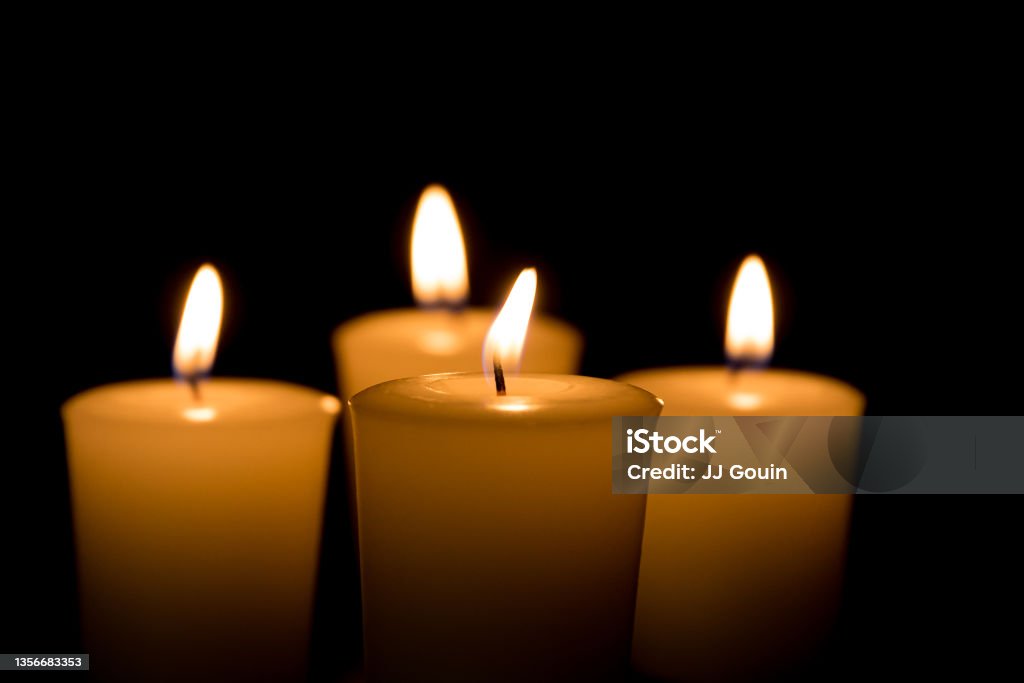 Soft focus of white candles burning, isolated on black background. Concept of religion, death, memoriam, and peace background, no people Obituary Stock Photo