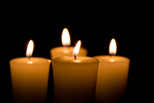 Soft focus of white candles burning, isolated on black background. Concept of religion, death, memoriam, and peace stock photo
