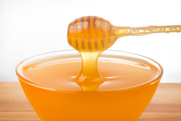 istock fresh honey dripping from a spoon into a transparent plate on a white background. organic vitamin health food 1356688584