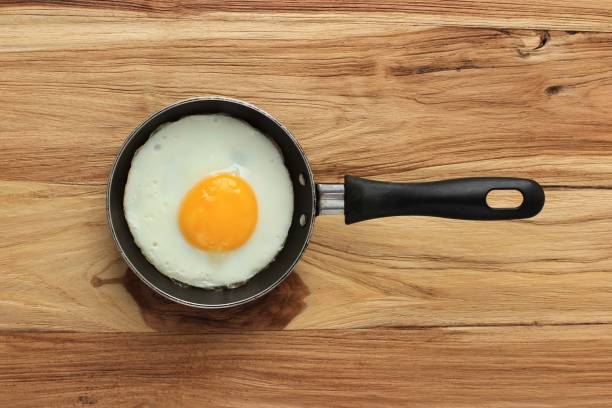 istock Sunny Side Egg with Perfect Round Yellow Egg Yolk. Top View on Wooden Table 1356696938