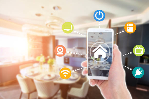 istock Smart home automation app on mobile with home interior in background. Internet of things concept at home. 1356699882