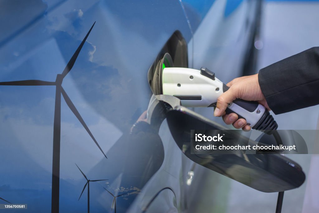 Double exposure of EV charging station for electric car in concept of green sustainable energy produced from renewable resources to supply to charger station in order to reduce CO2 emission . Sustainable Energy Stock Photo