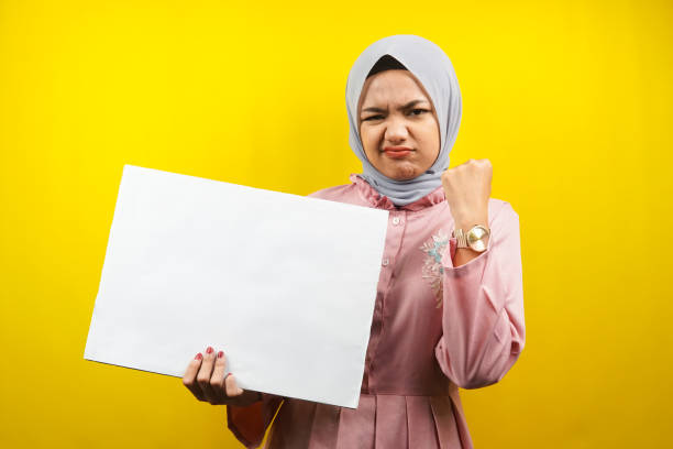 Pretty young muslim woman cheerful holding blank empty banner, placard, white board, blank sign board, white advertisement board, presenting something in copy space, promotion stock photo