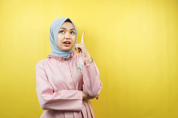 Beautiful young muslim woman getting idea, pointing up, isolated stock photo