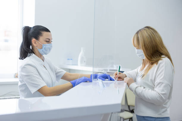 una recepcionista en un hospital moderno ayuda a una paciente joven a completar documentos. consentimiento para el tratamiento de datos personales - personal data assistant fotografías e imágenes de stock