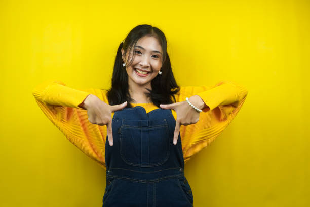 istock Pretty and cute young woman cheerful, confident, with hand pointing down at empty space, click link below, presenting something, promoting product, advertisement, isolated 1356703764