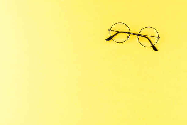 istock Overhead shot of round eyeglasses on yellow table with copyspace 1356716341