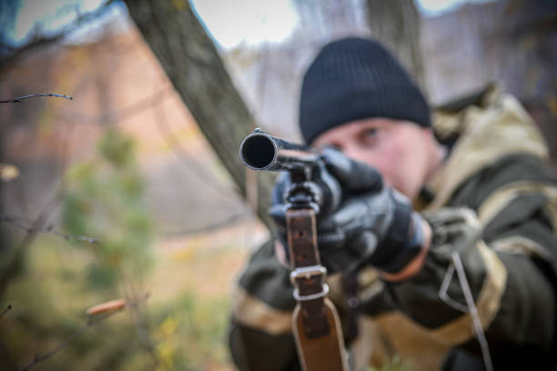 A man aiming with a pump-action shotgun. An armed man fires a shotgun. The military man works out the techniques of the stem.