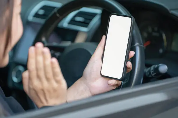 Female hand using smartphone in a car. Smartphones in-car use for Navigate or GPS. Mobile phone with isolated white screen. Blank empty screen. copy space. Empty space for text.