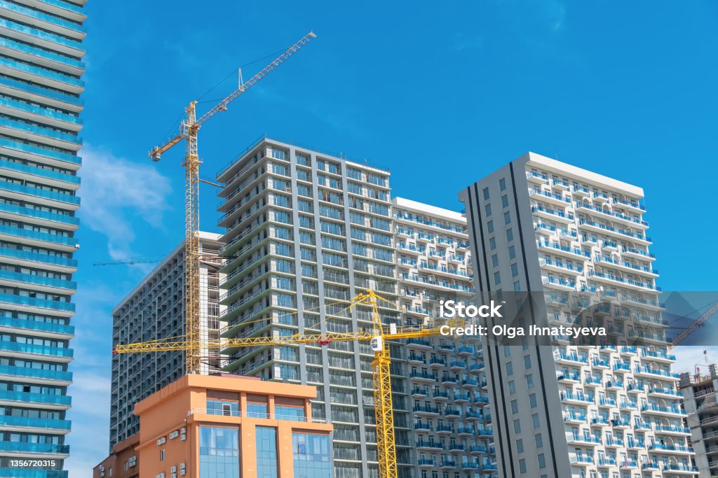 Construction of buildings in the city of Batumi, new Boulevard. Construction crane, multi-storey buildings, hotels, construction site on a sunny bright day against the blue sky Construction Industry Stock Photo