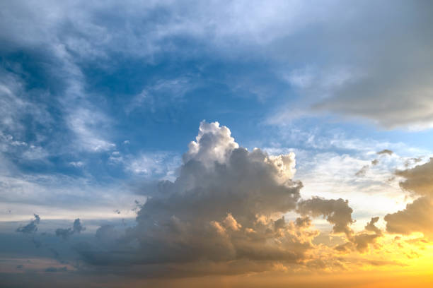 istock Dramatic moody sunset landscape with puffy clouds lit by yellow setting sun and blue sky. 1356722467