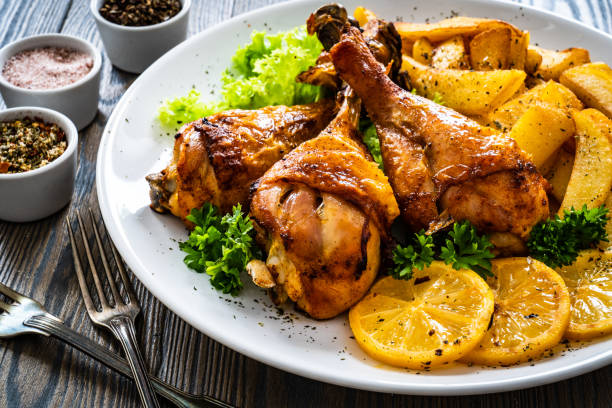 istock Barbecue chicken drumsticks with chips, lemon and greens on wooden table 1356722673