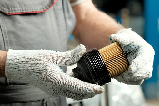 An auto mechanic replaces the oil filter during car maintenance at the service center.