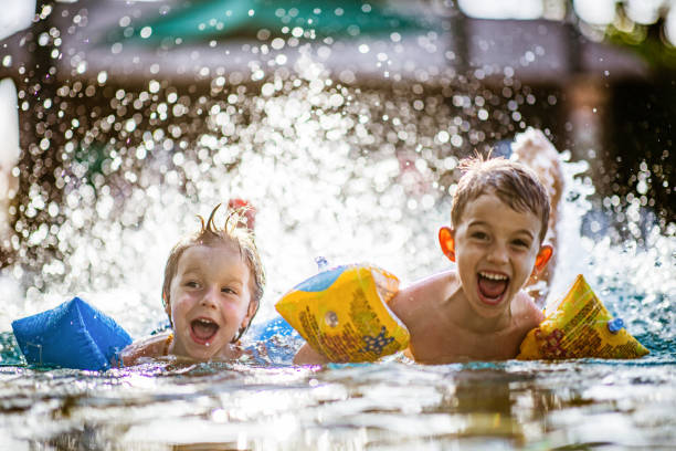 istock Happy little boys having fun while splashing water in summer day. 1356725241