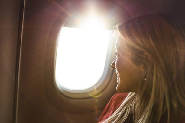istock Young happy woman looking through window during her flight by plane. 1356725427