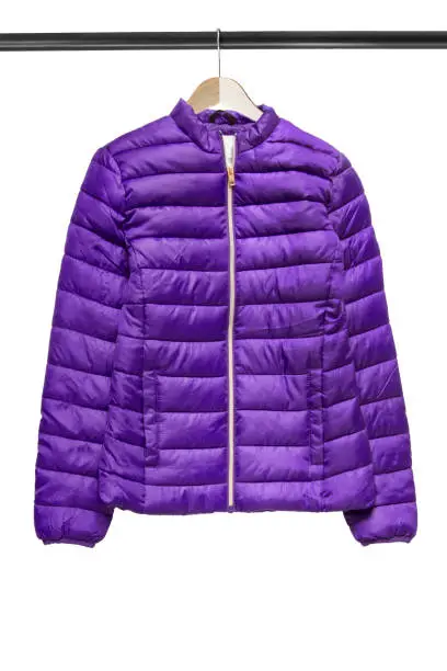 Purple sport puffer jacket hanging on clothes rack isolated over white
