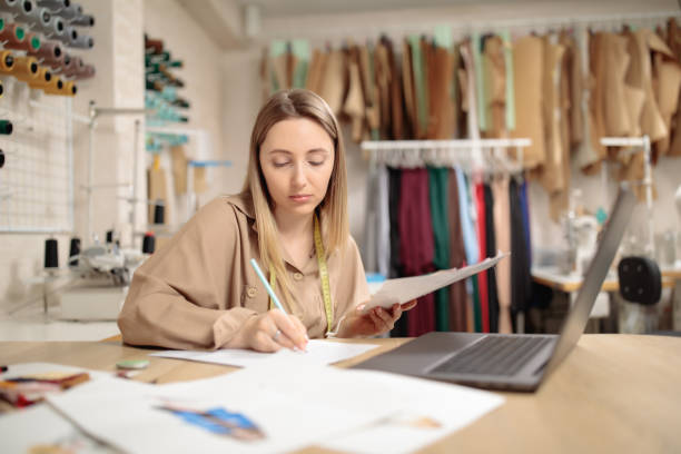 istock Got an idea. Interested millennial lady sitting at desk in workshop studio drawing sketch near laptop screen. 1356733482