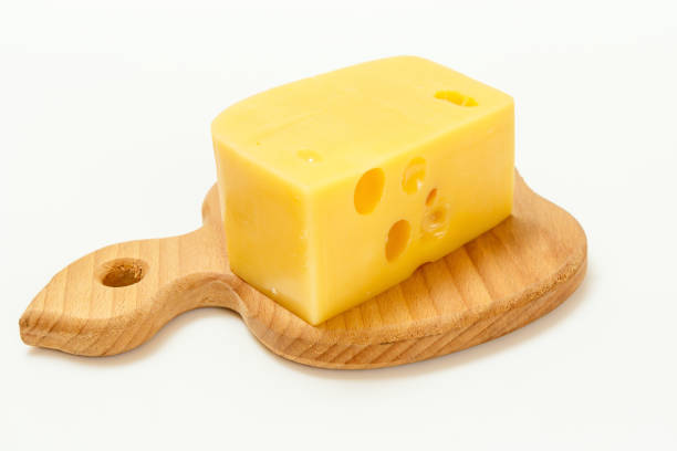 istock Slice of cheese on wooden cutting board on white background 1356734410