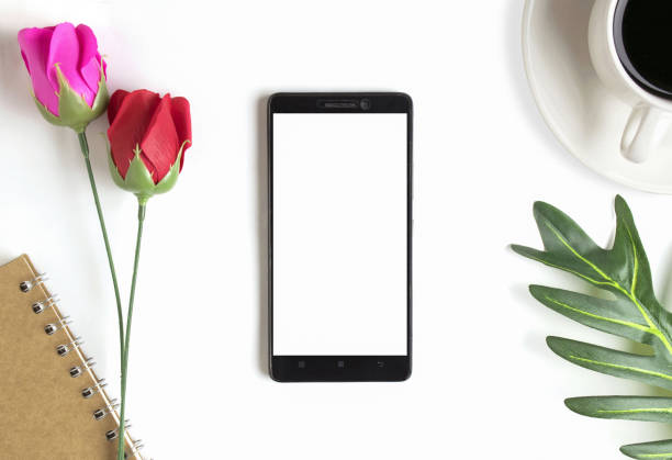 istock Office Desk table work space with Smartphone,Leaves, red roses, pink roses, coffee cups. 1356736642