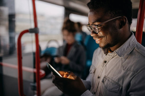 istock Young smiling man using phone in city bus 1356740774