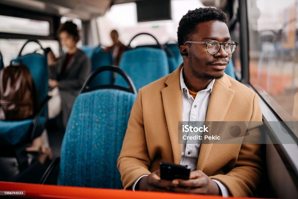 Young handsome businessman in public bus Young handsome man on public bus using mobile phone Bus Stock Photo