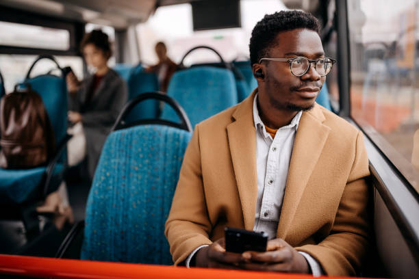 Young handsome businessman in public bus Young handsome man on public bus using mobile phone bus stock pictures, royalty-free photos & images