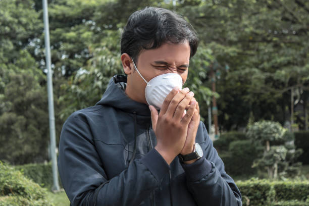 istock Asian man wearing protective mask and sneezing 1356741043