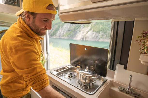 istock Living the van life, young man inside camper van cooking 1356743612