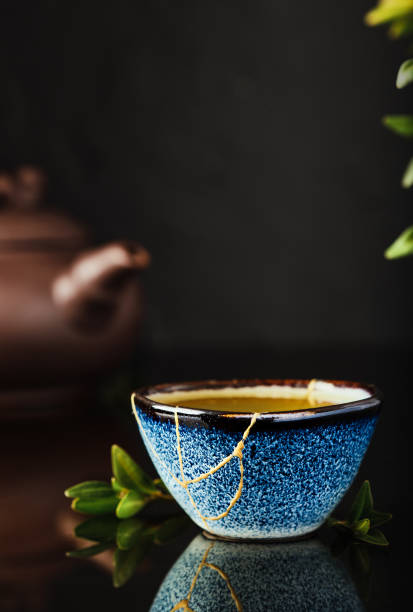 Cup of green Japanese tea on a dark background. Selective focus on the cup. Reclaimed ceramic blue cup, second life of things, recycling or kintsugi stock photo