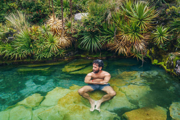 istock Young man swimming in a hot springs  water 1356747191