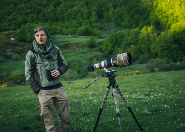 istock Photographer uses binoculars in a mountain meadow 1356749830