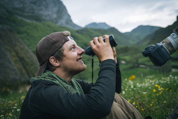 istock Photographer uses binoculars in a mountain meadow 1356749921